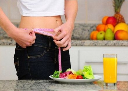 A girl who loses weight on a diet measures her waist size